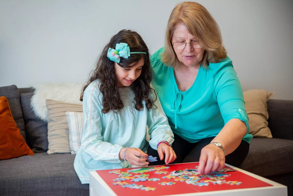 Child and grandmother putting together a jigsaw puzzle