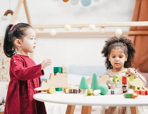 Twee kinderen spelen met houten speelgoed op kleine tafel