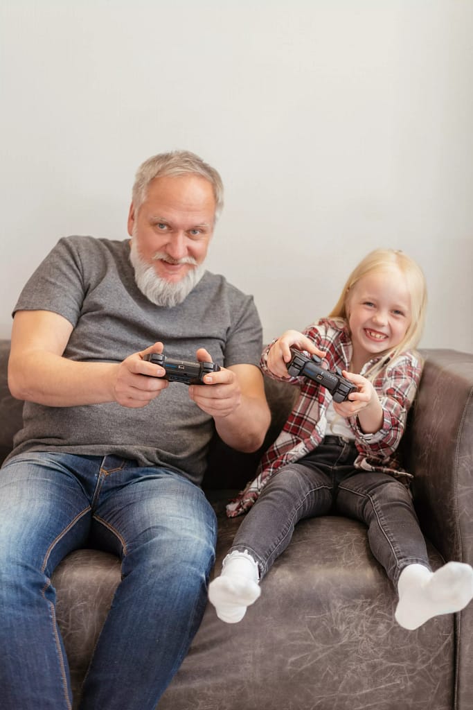 Man and child playing console game in sofa