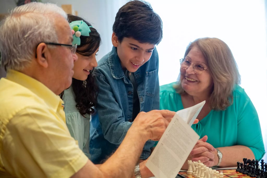 Grandparents and children reading manual of chess game